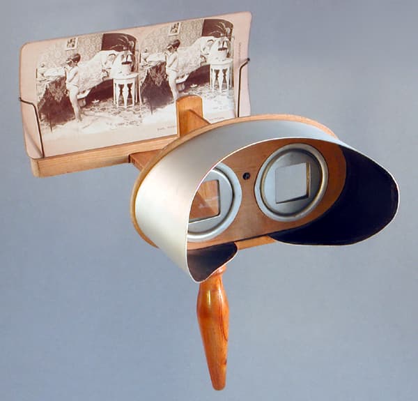 A Holmes-type stereoscope: a handheld wooden viewer with two lenses and a stand that holds a stereo card.