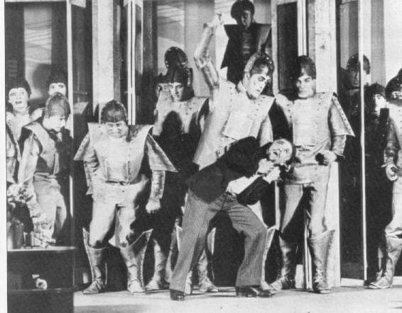 A black-and-white photograph from a 1920s stage production of R.U.R., showing actors in mechanical-looking costumes.