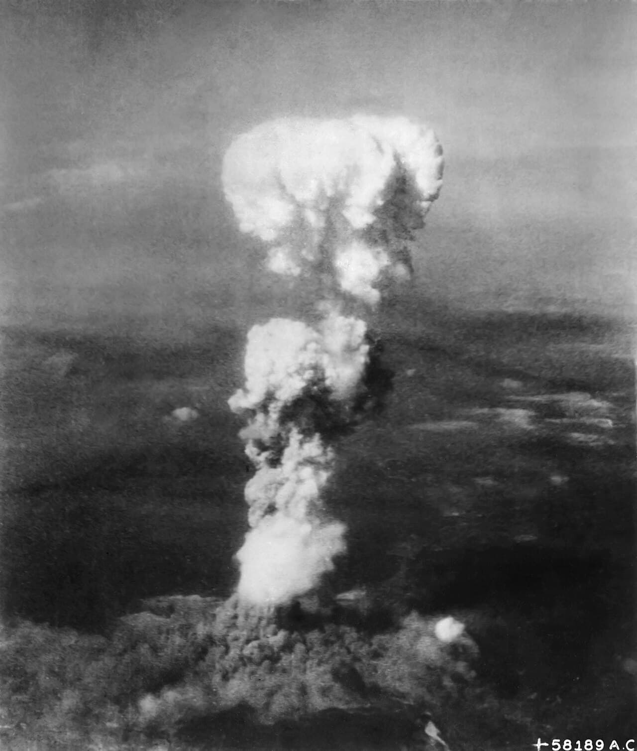 Black-and-white photo of a massive mushroom-shaped cloud rising over Hiroshima after the atomic bombing.