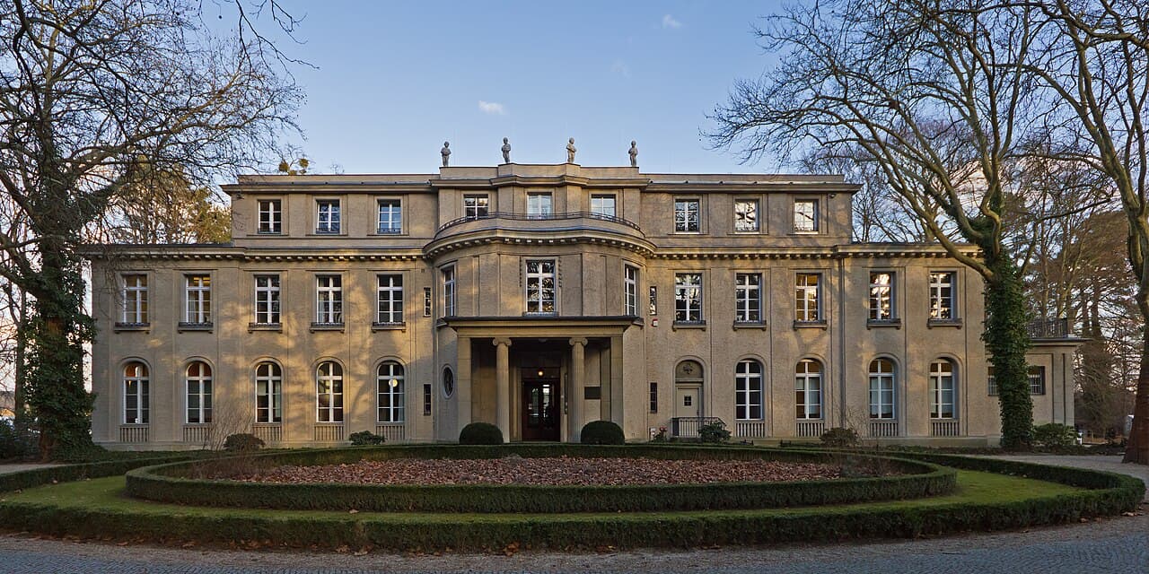 Photo of a grand lakeside villa with white walls and a red tile roof, now a Holocaust memorial site.