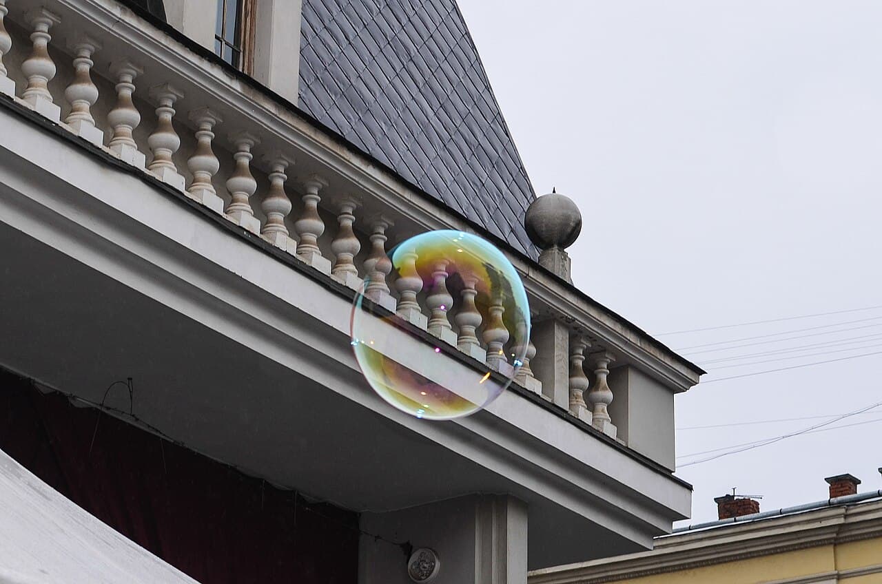A round soap bubble floating in the air, reflecting iridescent colors across its spherical surface.