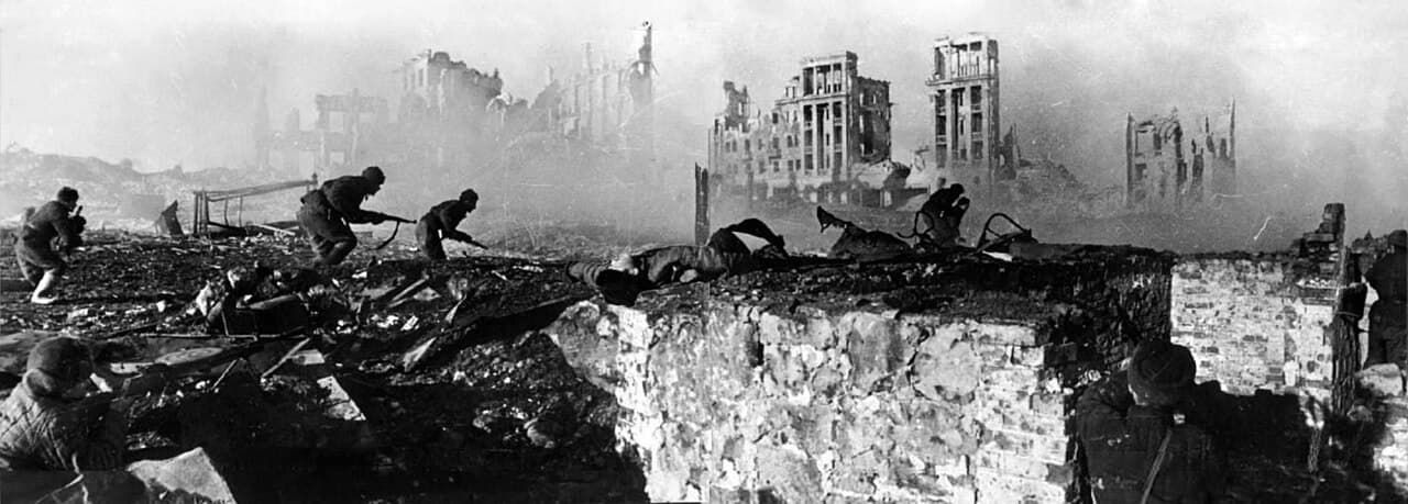 Black-and-white photo of Soviet soldiers advancing through the bombed-out ruins of a building in Stalingrad.