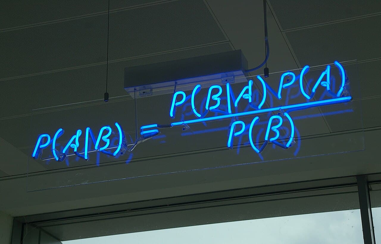 Bayes' theorem written in glowing blue neon tubes on a wall: P of A given B equals P of B given A times P of A, over P of B.