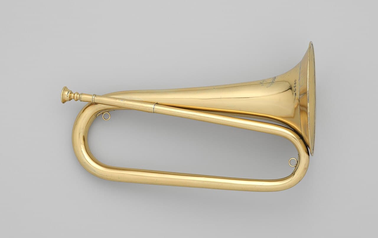 A coiled brass bugle with a flared bell and no valves, photographed against a plain background.
