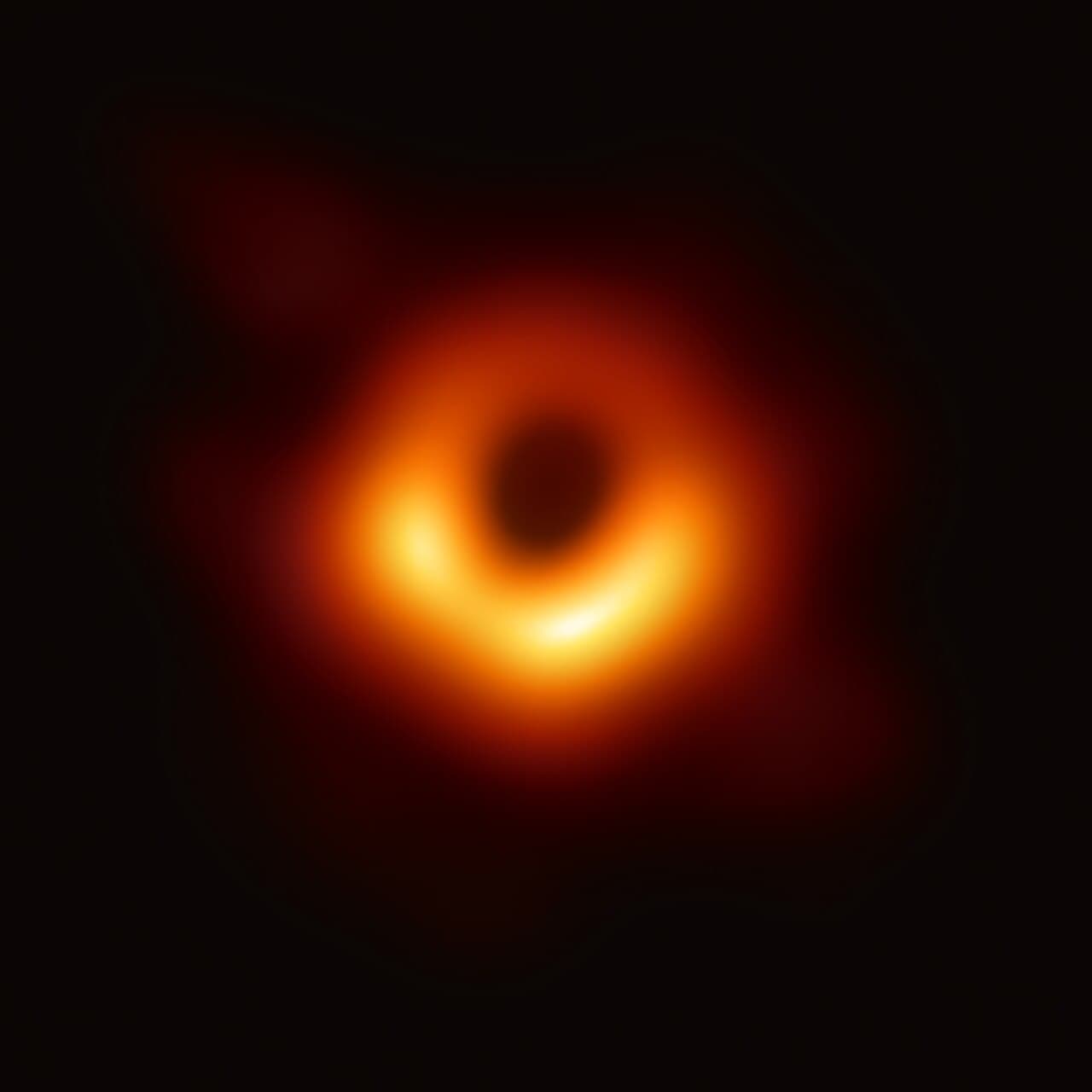 A blurry orange ring of glowing gas around a dark central shadow, against a black background.