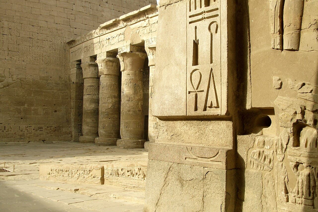 Rows of carved and painted Egyptian hieroglyphs covering a stone wall at the Temple of Ramesses III in Medinet Habu.