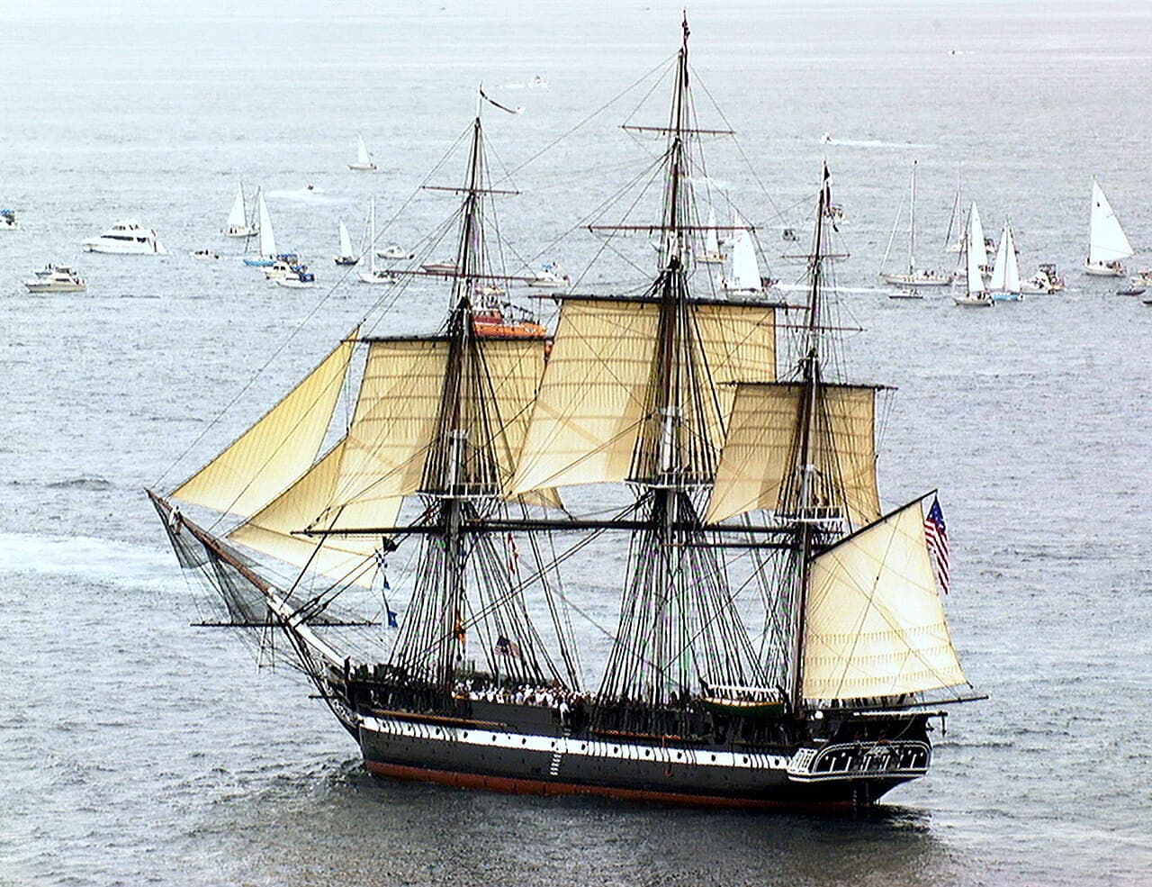 The three-masted wooden frigate USS Constitution under full sail on a calm sea.