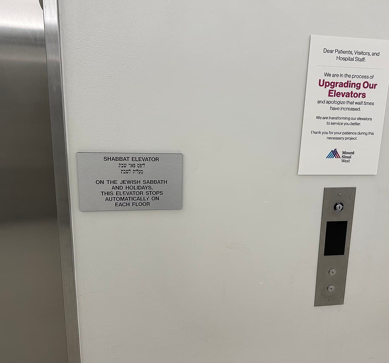 A metal sign next to elevator doors reads 'Shabbat elevator: on the Jewish Sabbath and holidays, this elevator stops automatically on each floor', in English and Hebrew.