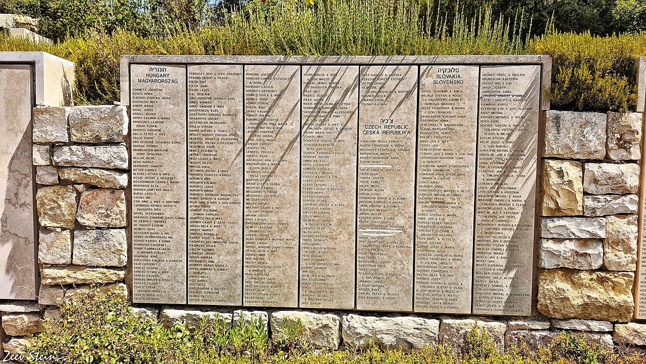 A wooded garden path lined with stone walls engraved with names, at the Garden of the Righteous Among the Nations at Yad Vashem.