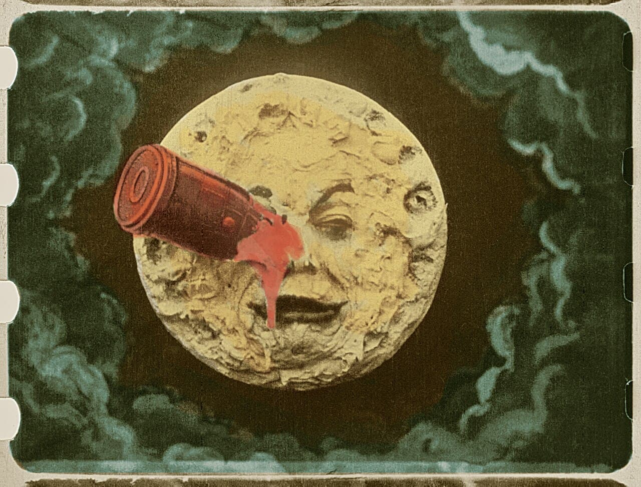 A hand-coloured film frame from A Trip to the Moon, showing a rocket lodged in the eye of a painted, personified Moon face.