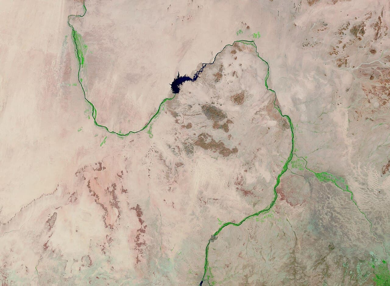 Satellite view of a thin dark-green strip along the Nile cutting through vast tan and reddish desert.